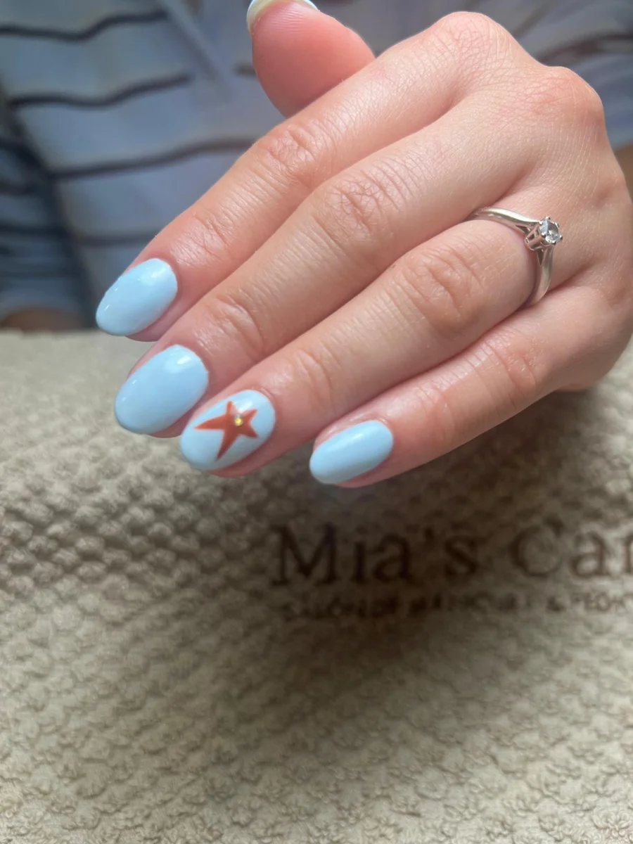 Manicura semipermanente azul cielo con estrella de mar decorada