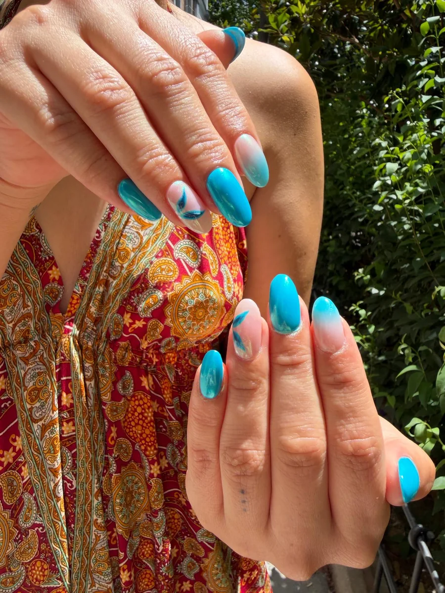 Nail art azul turquesa con degradado y hojas, forma almendra